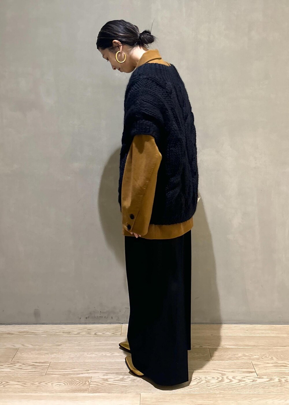 ブラック系のニット/セーター、ゴールド系のブーツ、イエロー系のブルゾンを着用したレディースの秋コーディネートの6枚目の写真