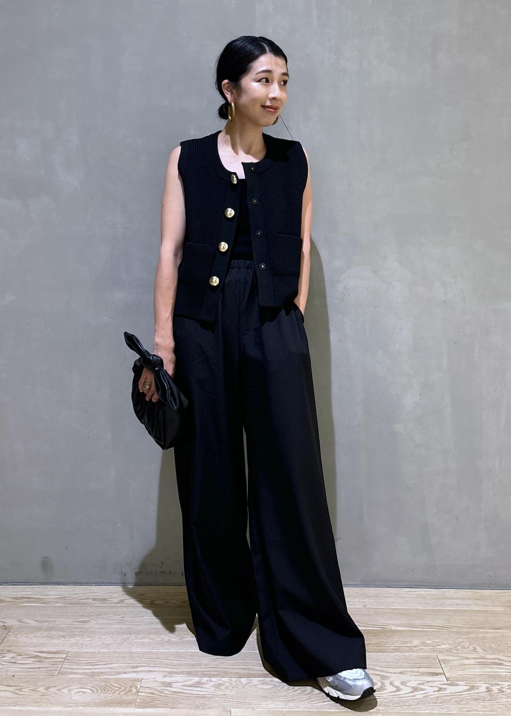 シルバー系のスニーカー、ブラック系のニット/セーター、ブラック系のショルダーバッグを着用したレディースの夏コーディネートの2枚目の写真