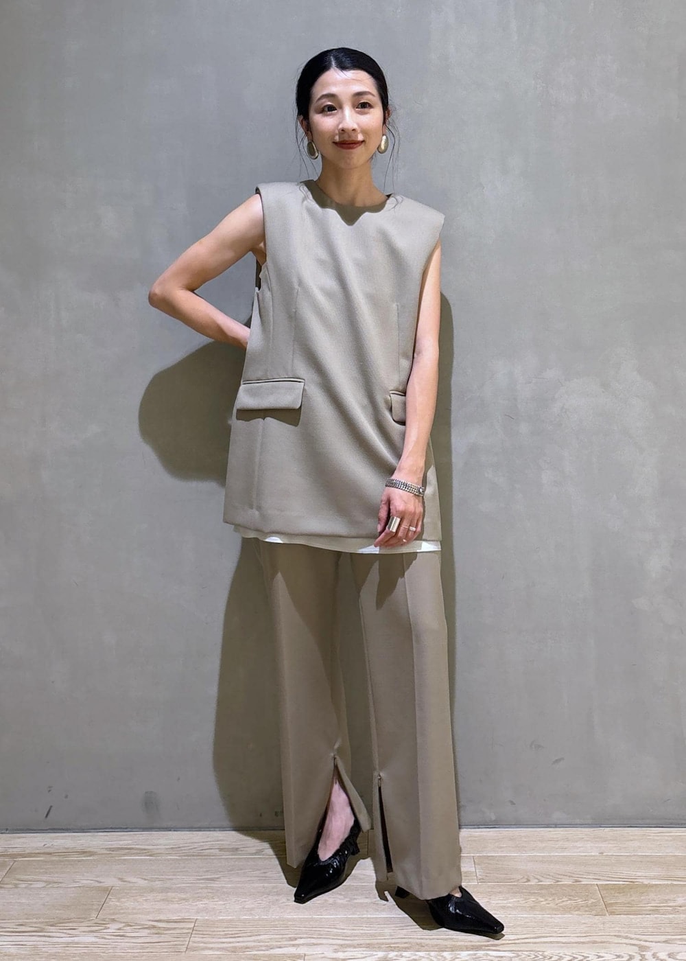 ブラック系のパンプス、ベージュ系のベスト、ベージュ系のスラックスを着用したレディースの夏コーディネートの2枚目の写真