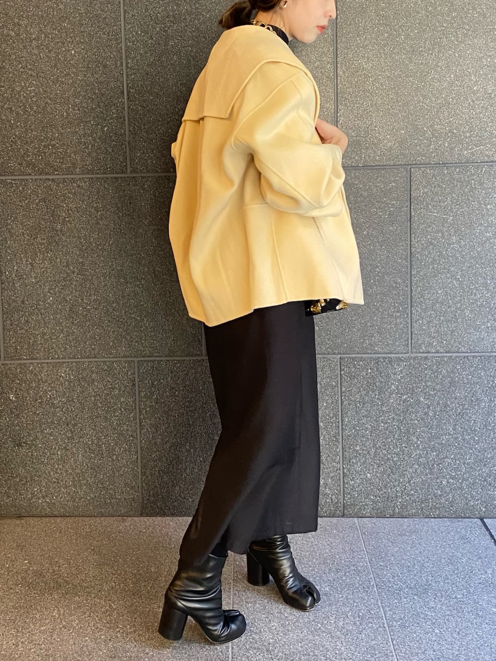 ブラック系のバッグ、ブラック系のワンピース、ブラック系のブーツを着用したレディースの春コーディネートの3枚目の写真