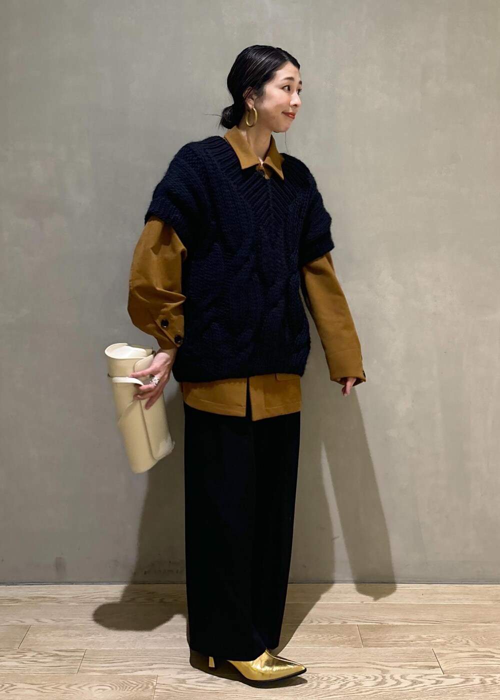 ブラック系のニット/セーター、ゴールド系のブーツ、イエロー系のブルゾンを着用したレディースの秋コーディネートの4枚目の写真