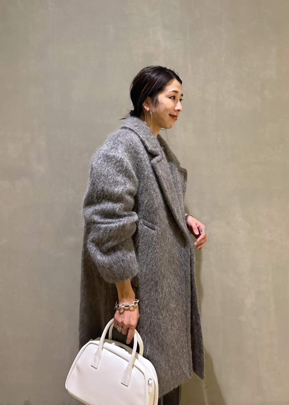 ホワイト系のボストンバッグ、グレー系のカーディガン/ボレロ、グレー系のチェスターコートを着用したレディースの秋コーディネートの9枚目の写真