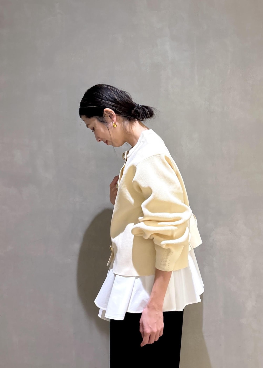 ホワイト系のパンプス、ブラック系のスラックス、ホワイト系のショルダーバッグを着用したレディースの冬コーディネートの9枚目の写真