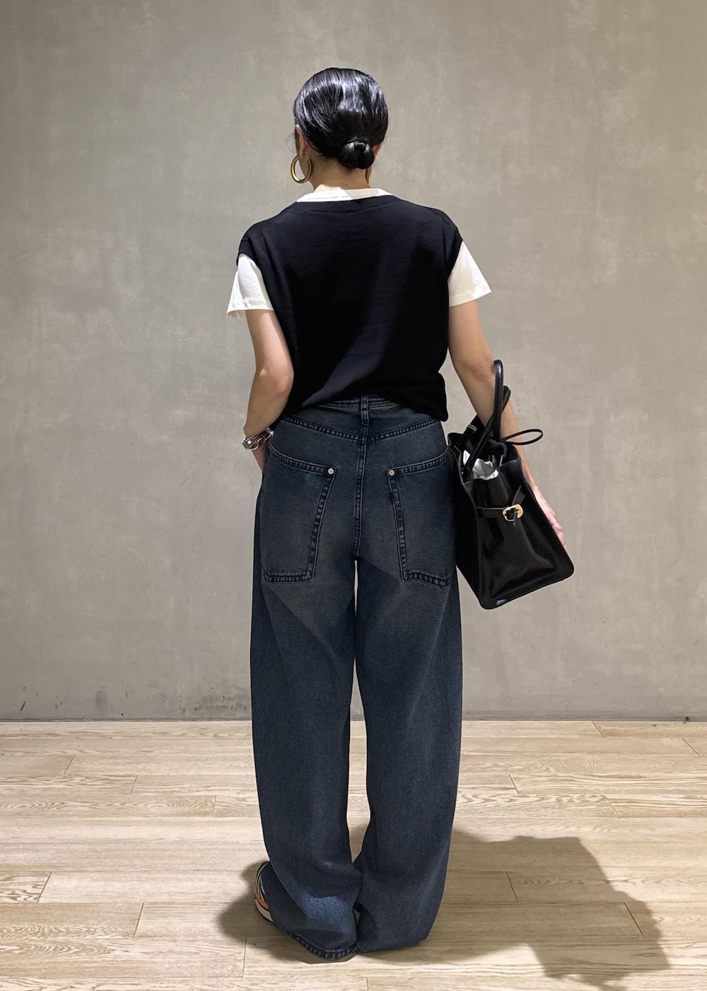 ブラック系のトートバッグ、ブラック系のTシャツ/カットソー、ブルー系のデニムパンツを着用したレディースの夏コーディネートの5枚目の写真