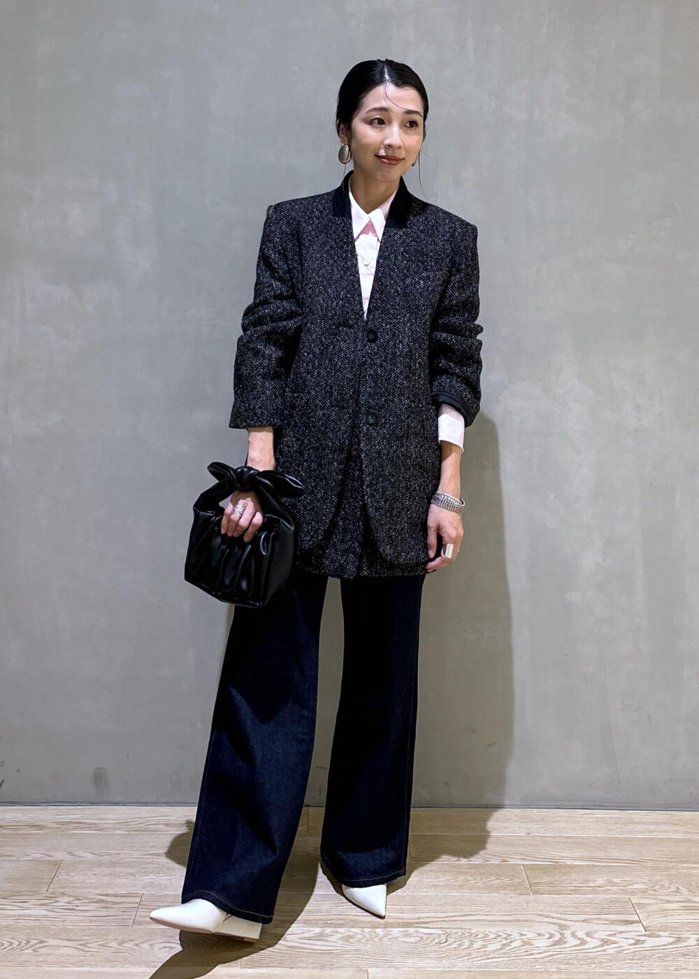 ブラック系のショルダーバッグ、ホワイト系のパンプス、ブルー系のデニムパンツを着用したレディースの夏コーディネートの2枚目の写真