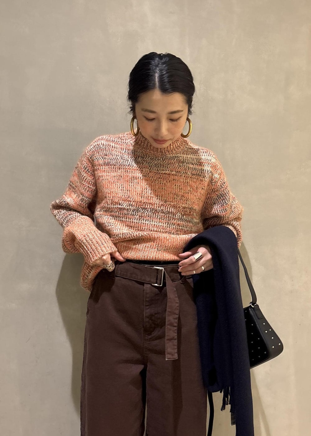 オレンジ系のニット/セーター、ブラック系のショルダーバッグ、ブラウン系のその他パンツを着用したレディースの秋コーディネートの8枚目の写真