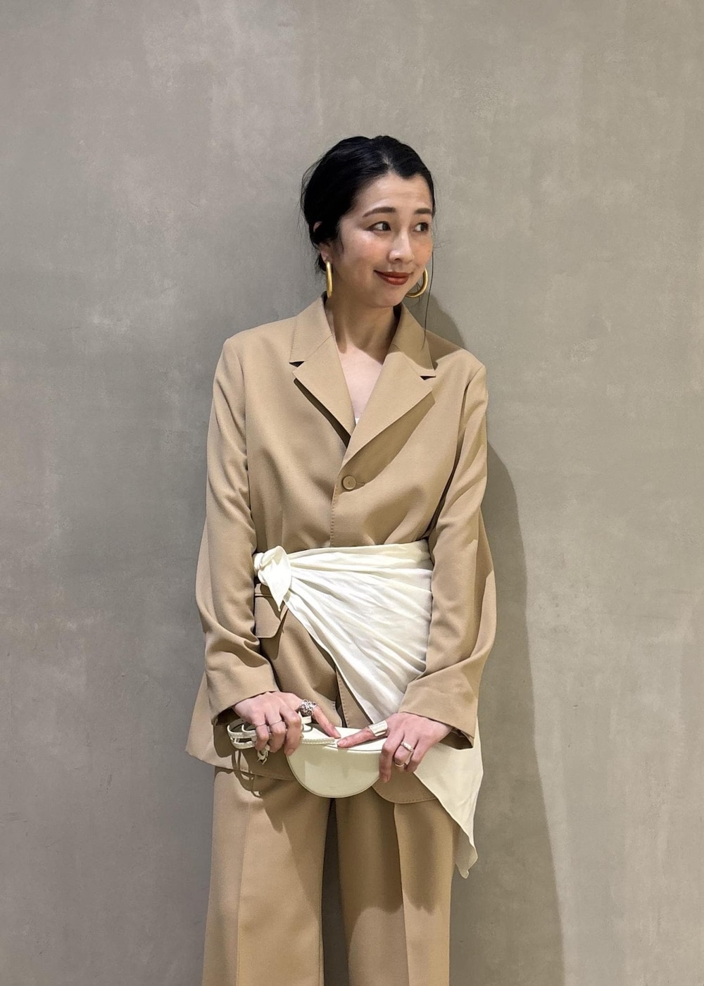 ベージュ系のテーラードジャケット、ホワイト系のシャツ/ブラウス、ベージュ系のスラックスを着用したレディースの冬コーディネートの8枚目の写真