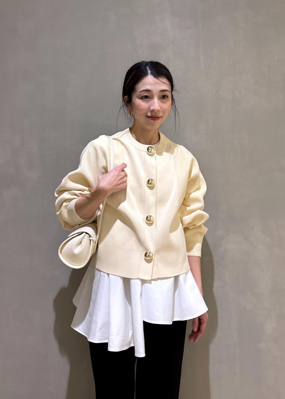 ホワイト系のパンプス、ブラック系のスラックス、ホワイト系のショルダーバッグを着用したレディースの冬コーディネートの8枚目の写真