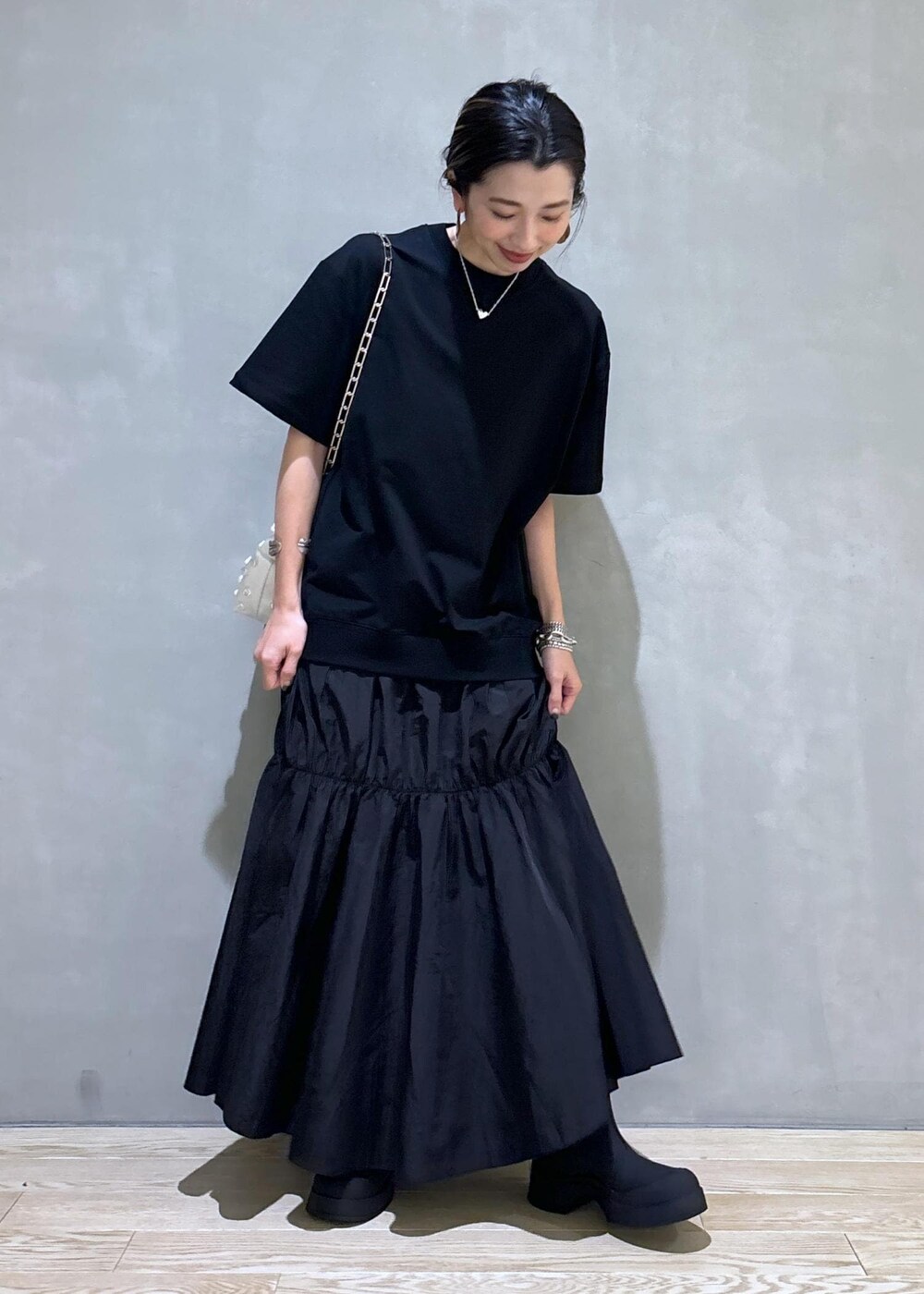 ホワイト系のショルダーバッグ、ブラック系のブーツ、ブラック系のワンピースを着用したレディースの夏コーディネートの3枚目の写真