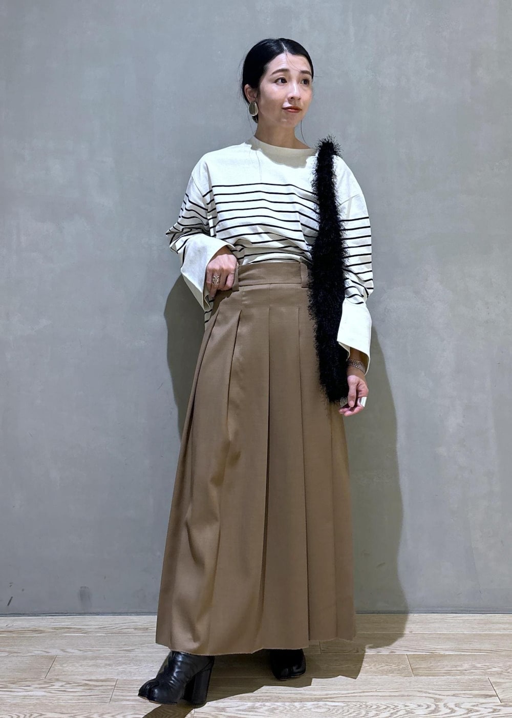 ベージュ系のスカート、ホワイト系のTシャツ/カットソー、ブラック系のハンドバッグを着用したレディースの夏コーディネートの2枚目の写真