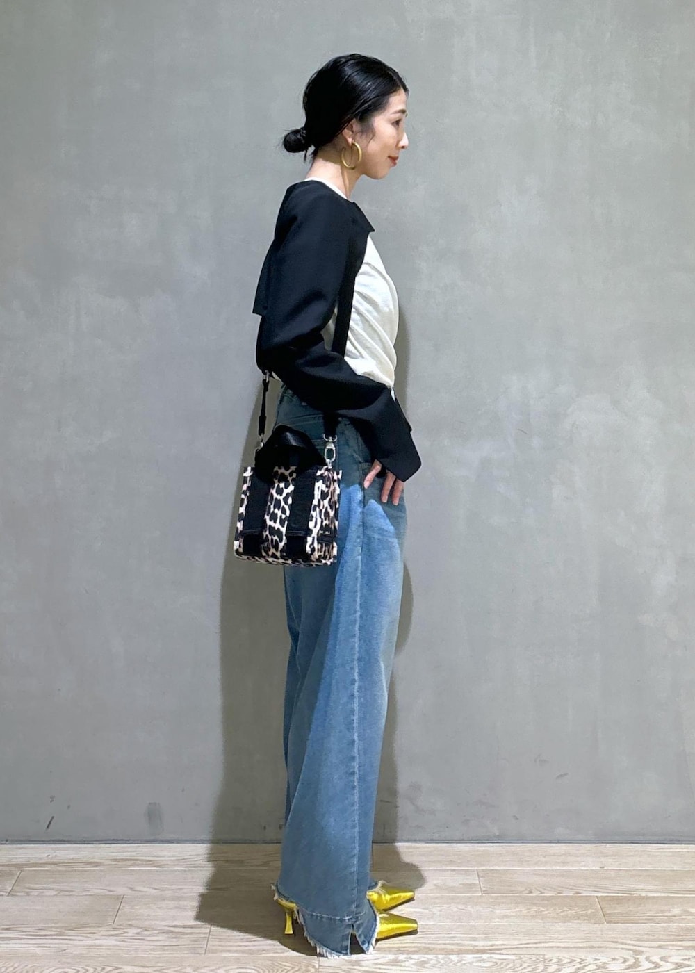 ブルー系のデニムパンツ、ゴールド系のパンプス、ブラック系のノーカラージャケットを着用したレディースの秋コーディネートの2枚目の写真