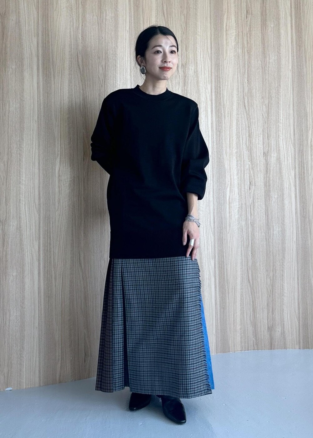 グレー系のスカート、ブラック系のブーツ、ブラック系のニット/セーターを着用したレディースの秋コーディネートの3枚目の写真