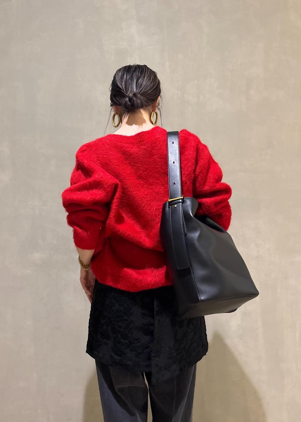 レッド系のニット/セーター、ブラック系のスカート、ブラック系のデニムパンツを着用したレディースの冬コーディネートの8枚目の写真