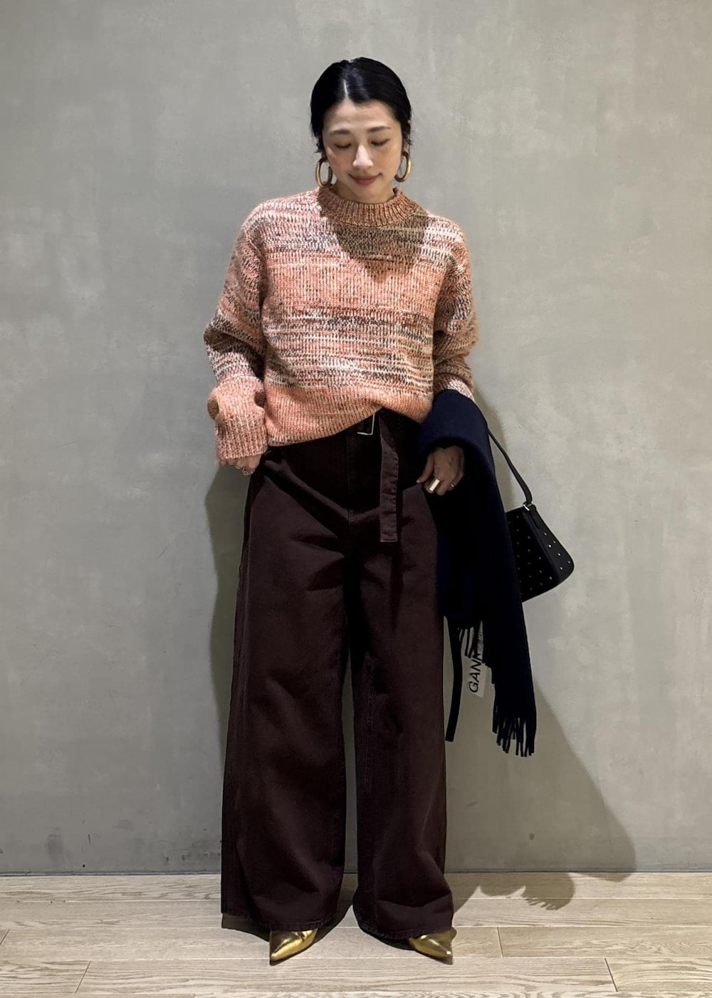 オレンジ系のニット/セーター、ブラック系のショルダーバッグ、ブラウン系のその他パンツを着用したレディースの秋コーディネートの3枚目の写真