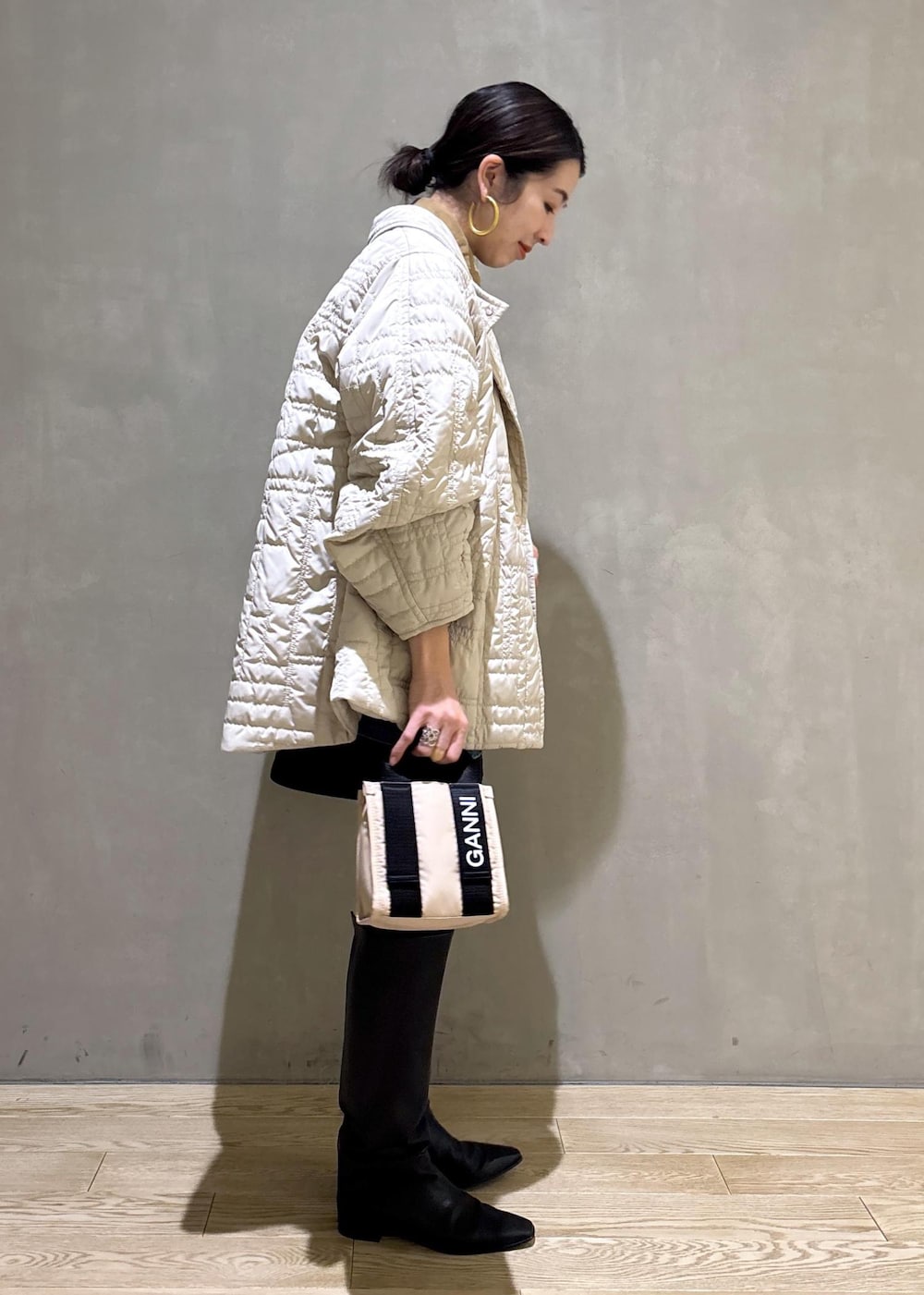 ベージュ系のトートバッグ、ブラック系のブーツ、ブラック系のスカートを着用したレディースの冬コーディネートの4枚目の写真