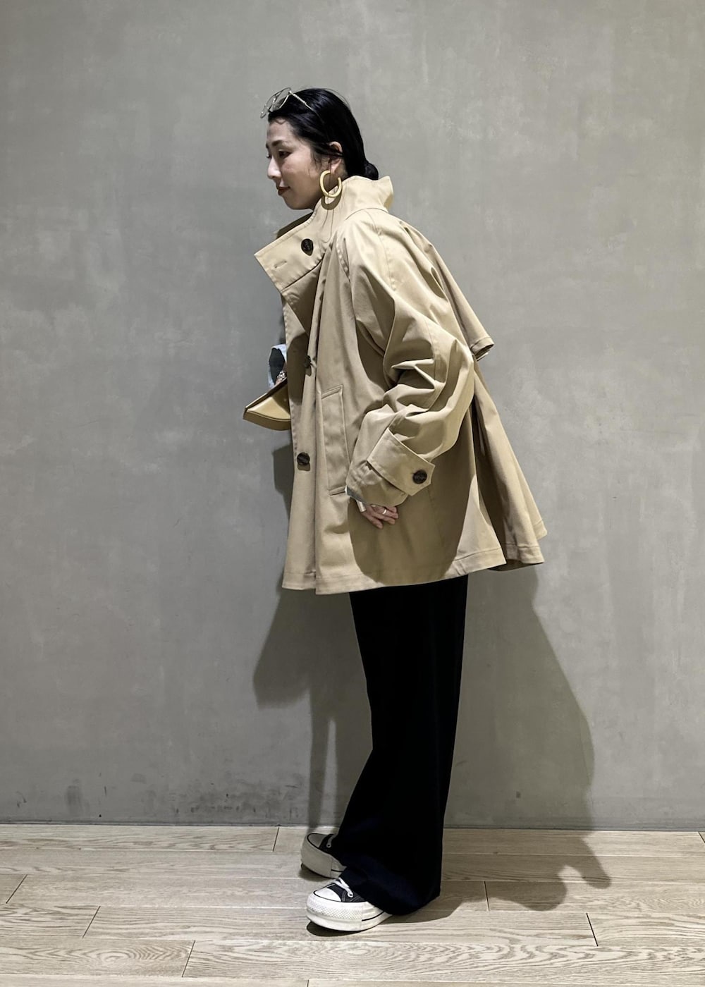 ベージュ系のトレンチコート、ブラック系のスラックス、イエロー系のキーホルダーを着用したレディースの冬コーディネートの6枚目の写真