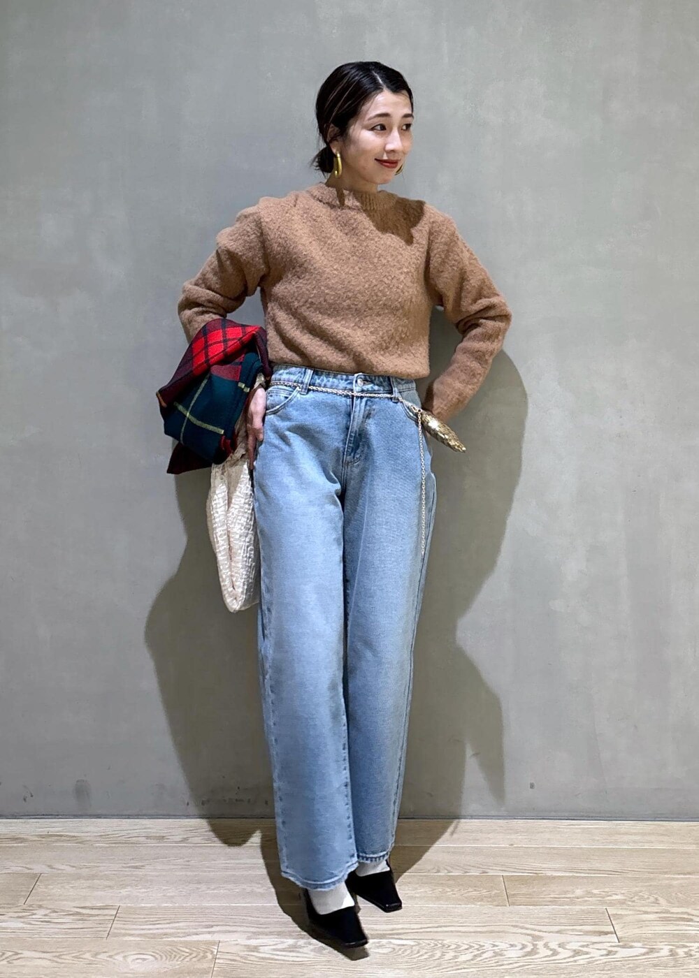 ホワイト系のハンドバッグ、ゴールド系のショルダーバッグ、ブルー系のデニムパンツを着用したレディースの冬コーディネートの4枚目の写真