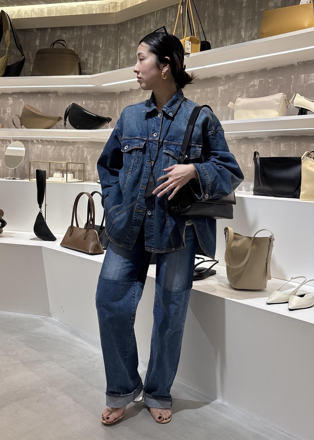 ブルー系のデニムジャケット、ブラック系のショルダーバッグ、ブルー系のデニムパンツを着用したレディースの春コーディネートの5枚目の写真
