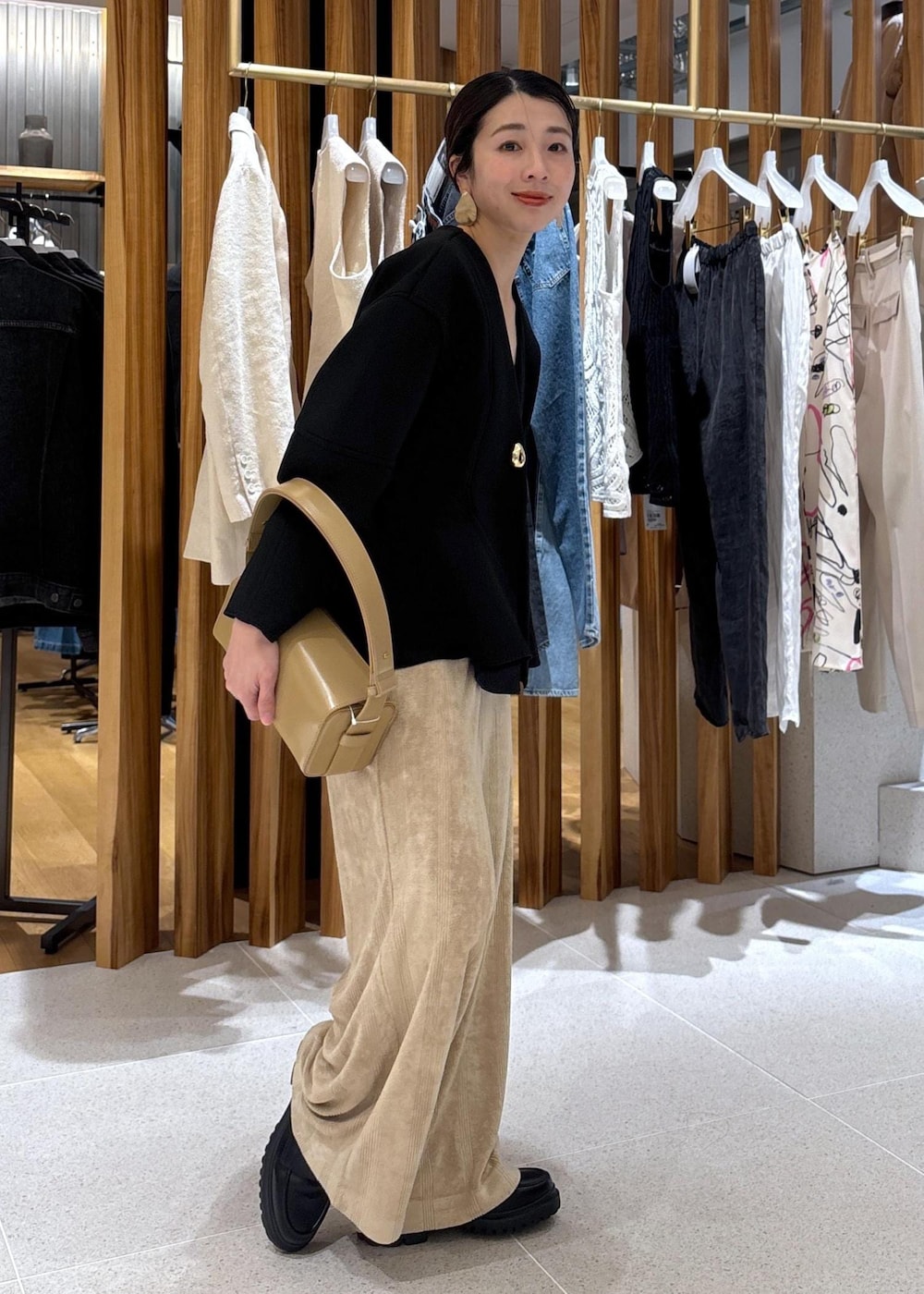 ベージュ系のハンドバッグ、ブラック系のローファー、ブラック系のカーディガン/ボレロを着用したレディースの冬コーディネートの5枚目の写真