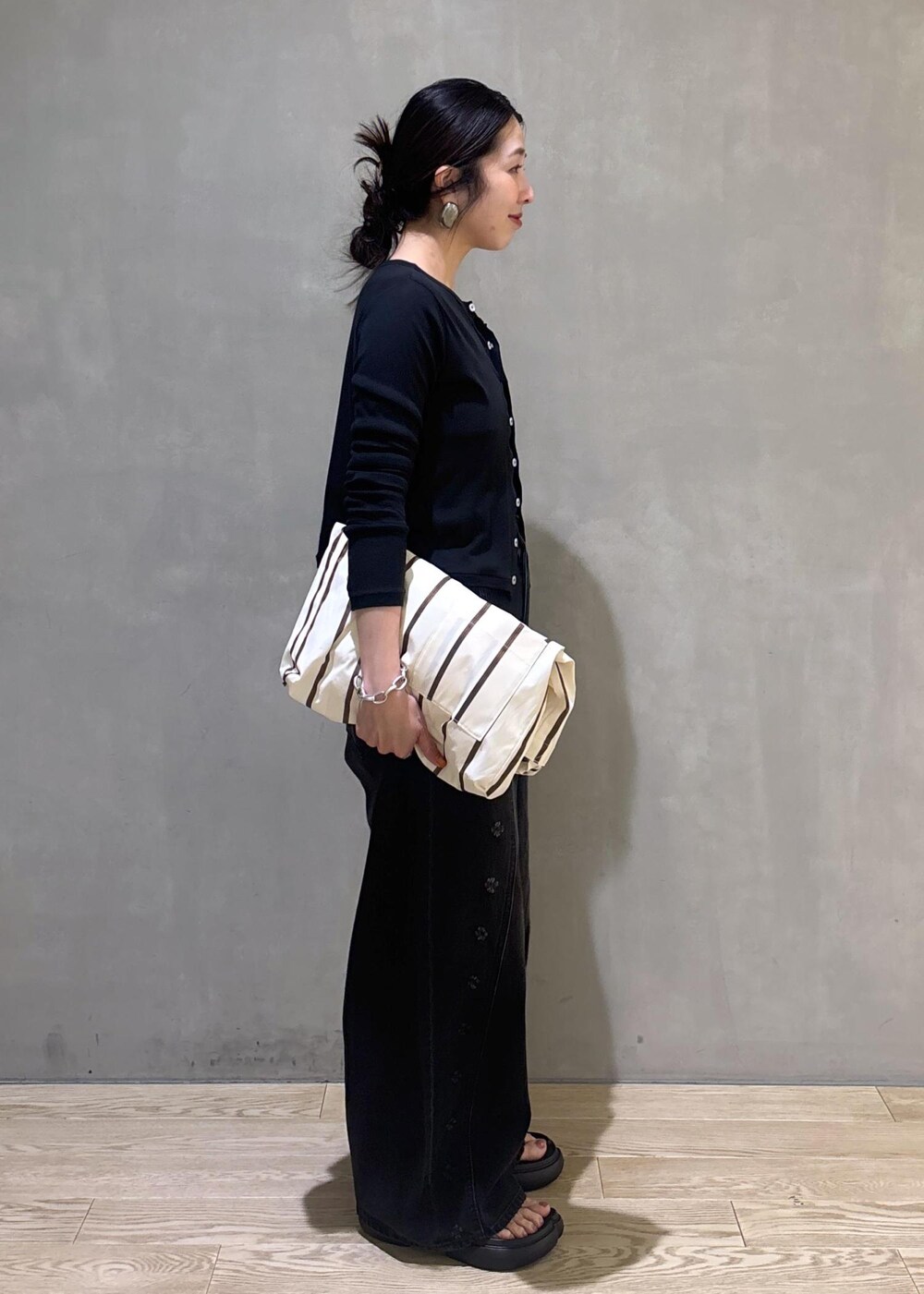 ブラック系のカーディガン/ボレロ、ホワイト系のショルダーバッグ、ブラック系のデニムパンツを着用したレディースの春コーディネートの2枚目の写真