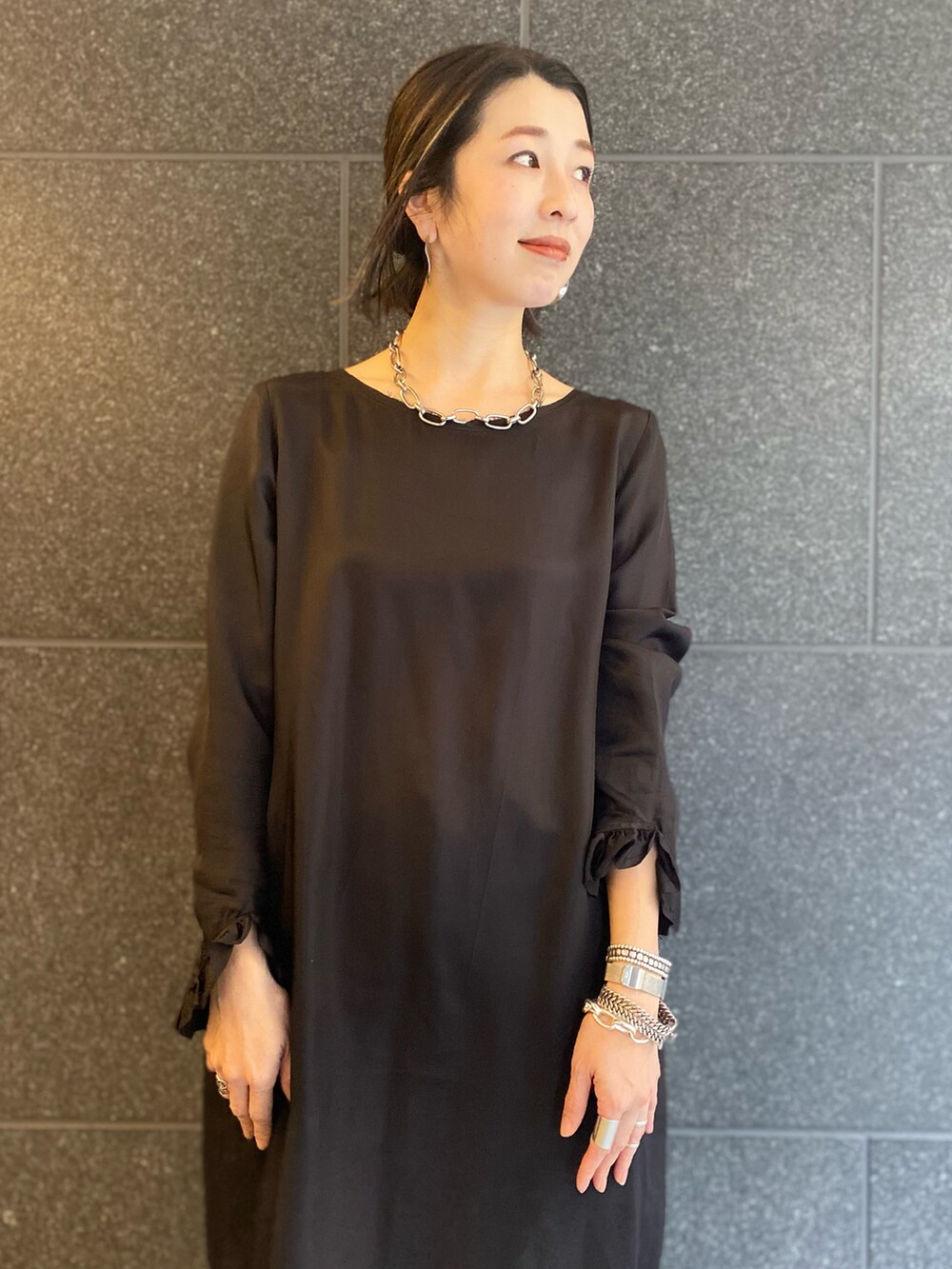 ホワイト系のショルダーバッグ、ブラック系のワンピース、シルバー系のネックレスを着用したレディースの春コーディネートの3枚目の写真