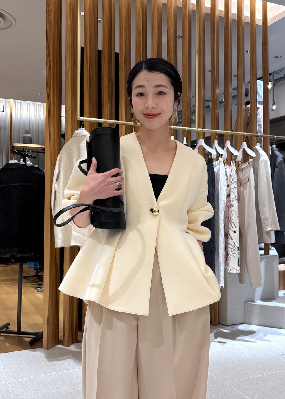 ブラック系のショルダーバッグ、ホワイト系のパンプス、ベージュ系のスラックスを着用したレディースの冬コーディネートの10枚目の写真