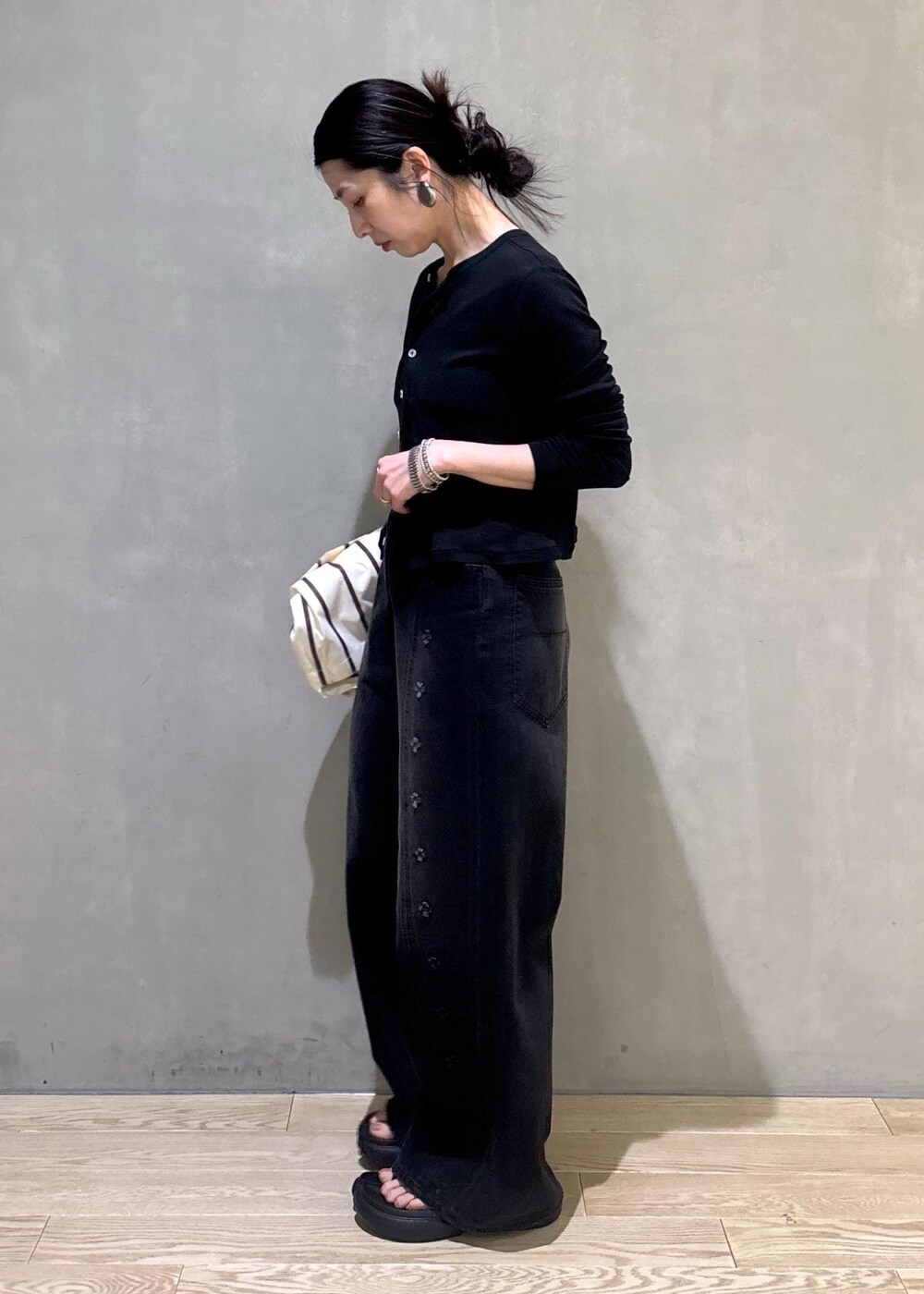 ブラック系のカーディガン/ボレロ、ホワイト系のショルダーバッグ、ブラック系のデニムパンツを着用したレディースの春コーディネートの4枚目の写真