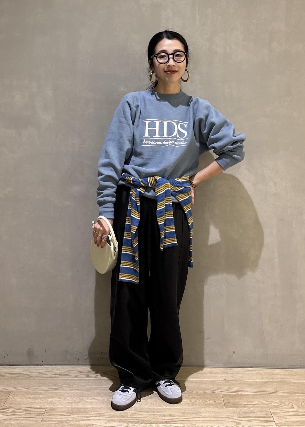 ホワイト系のハンドバッグ、ブルー系のスウェット、ブルー系のポロシャツを着用したレディースの秋コーディネートの2枚目の写真