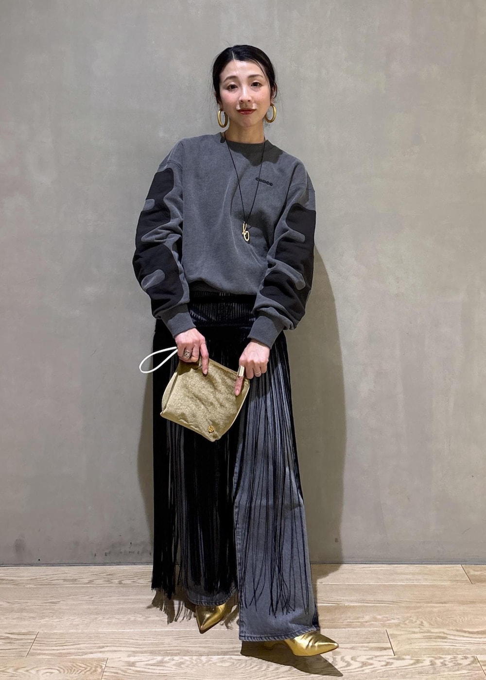 ブラック系のデニムパンツ、ブラック系のスカート、ベージュ系のポーチを着用したレディースの冬コーディネートの3枚目の写真