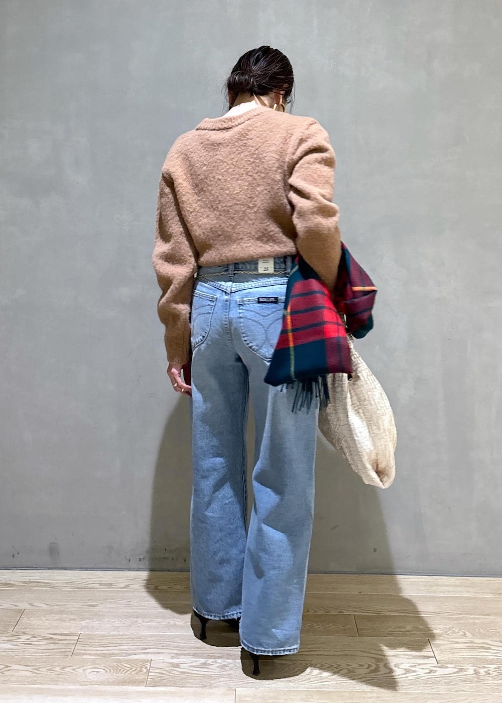 ホワイト系のハンドバッグ、ゴールド系のショルダーバッグ、ブルー系のデニムパンツを着用したレディースの冬コーディネートの6枚目の写真