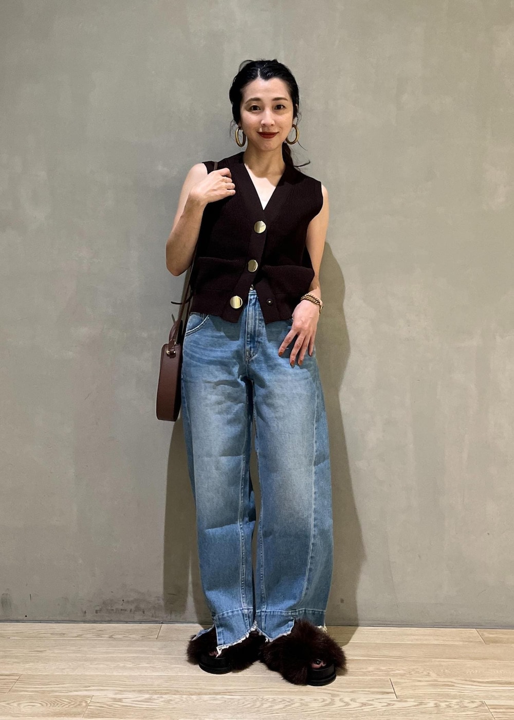 ブルー系のデニムパンツ、ブラウン系のサンダル、ブラウン系のベストを着用したレディースの夏コーディネートの5枚目の写真