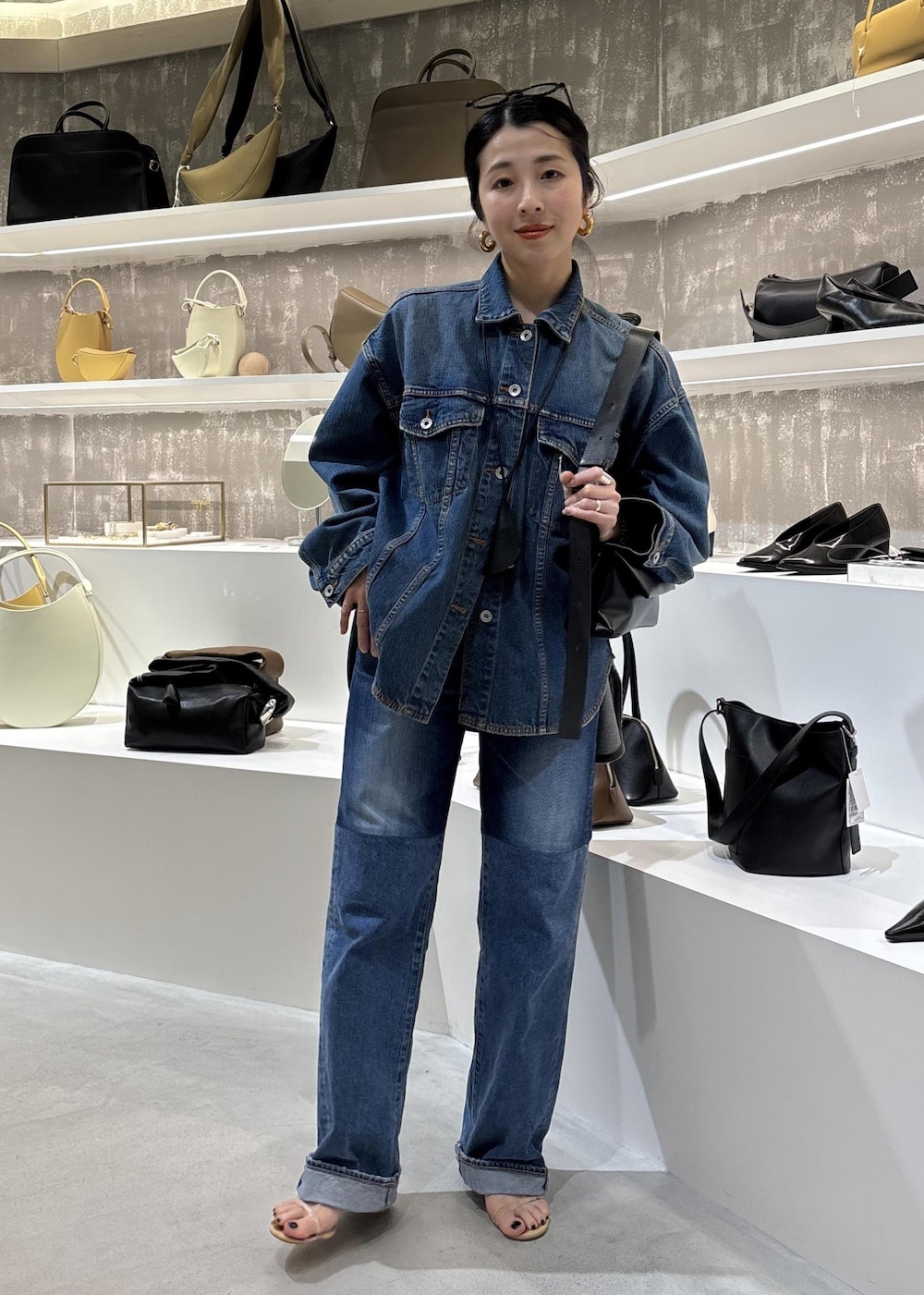 ブルー系のデニムジャケット、ブラック系のショルダーバッグ、ブルー系のデニムパンツを着用したレディースの春コーディネートの2枚目の写真