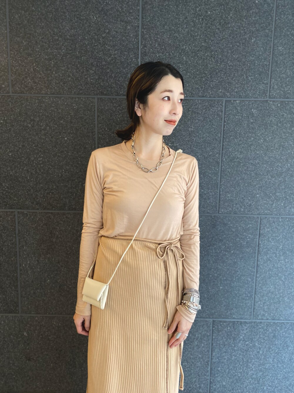 ベージュ系のTシャツ/カットソー、ベージュ系のスカート、ホワイト系のショルダーバッグを着用したレディースの春コーディネートの2枚目の写真