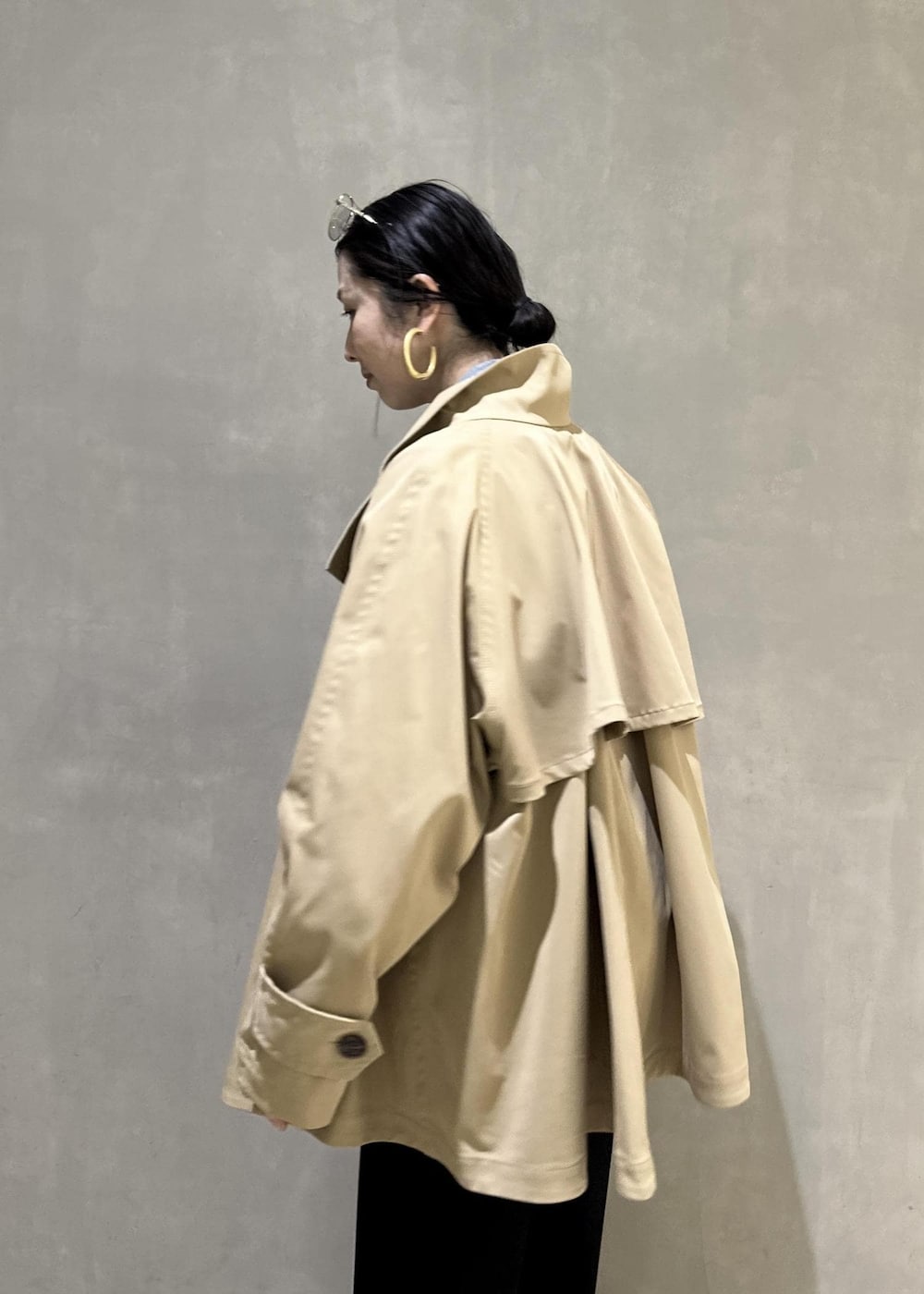 ベージュ系のトレンチコート、ブラック系のスラックス、イエロー系のキーホルダーを着用したレディースの冬コーディネートの10枚目の写真