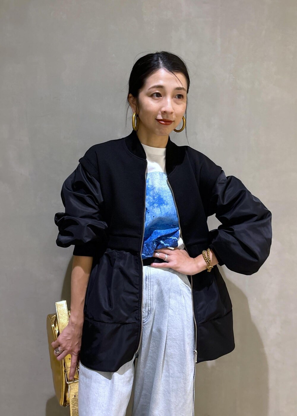ゴールド系のショルダーバッグ、ブラック系のブルゾン、ホワイト系のTシャツ/カットソーを着用したレディースの秋コーディネートの9枚目の写真