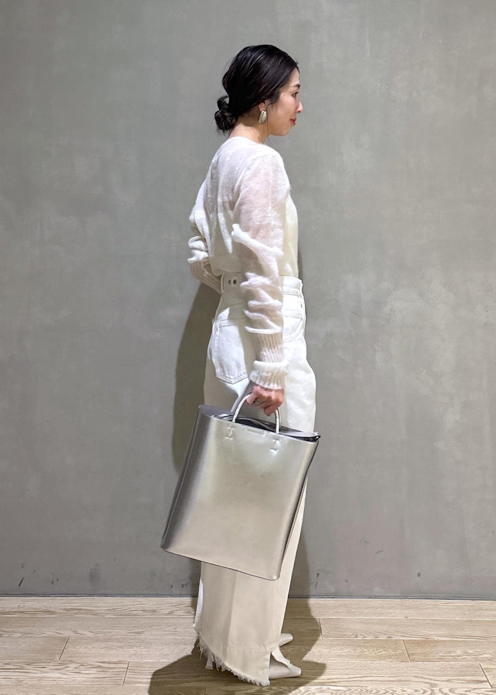 ホワイト系のパンプス、シルバー系のトートバッグ、ホワイト系のデニムパンツを着用したレディースの冬コーディネートの4枚目の写真