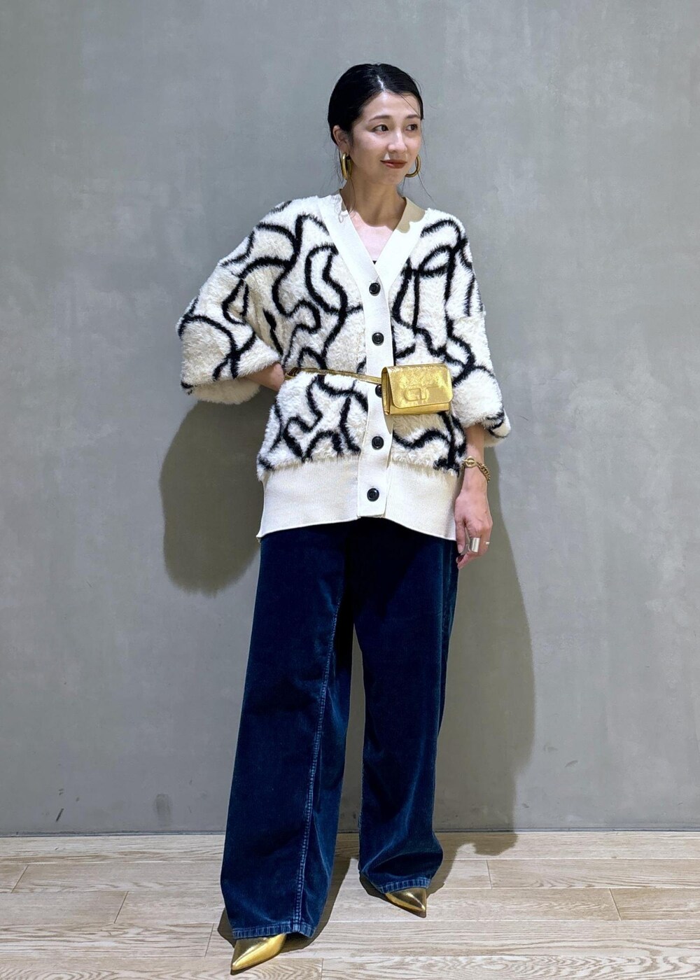 ゴールド系のその他シューズ、ゴールド系のショルダーバッグ、ホワイト系のカーディガン/ボレロを着用したレディースの秋コーディネートの3枚目の写真