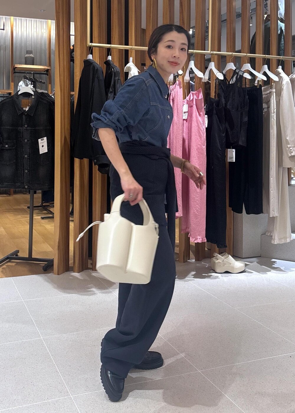 ブラック系のローファー、ホワイト系のハンドバッグ、ブルー系のブルゾンを着用したレディースの春コーディネートの2枚目の写真