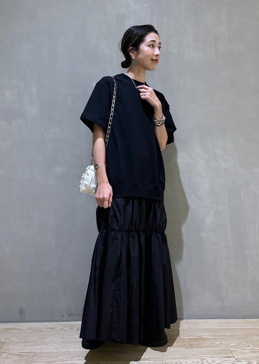 ホワイト系のショルダーバッグ、ブラック系のブーツ、ブラック系のワンピースを着用したレディースの夏コーディネートの5枚目の写真