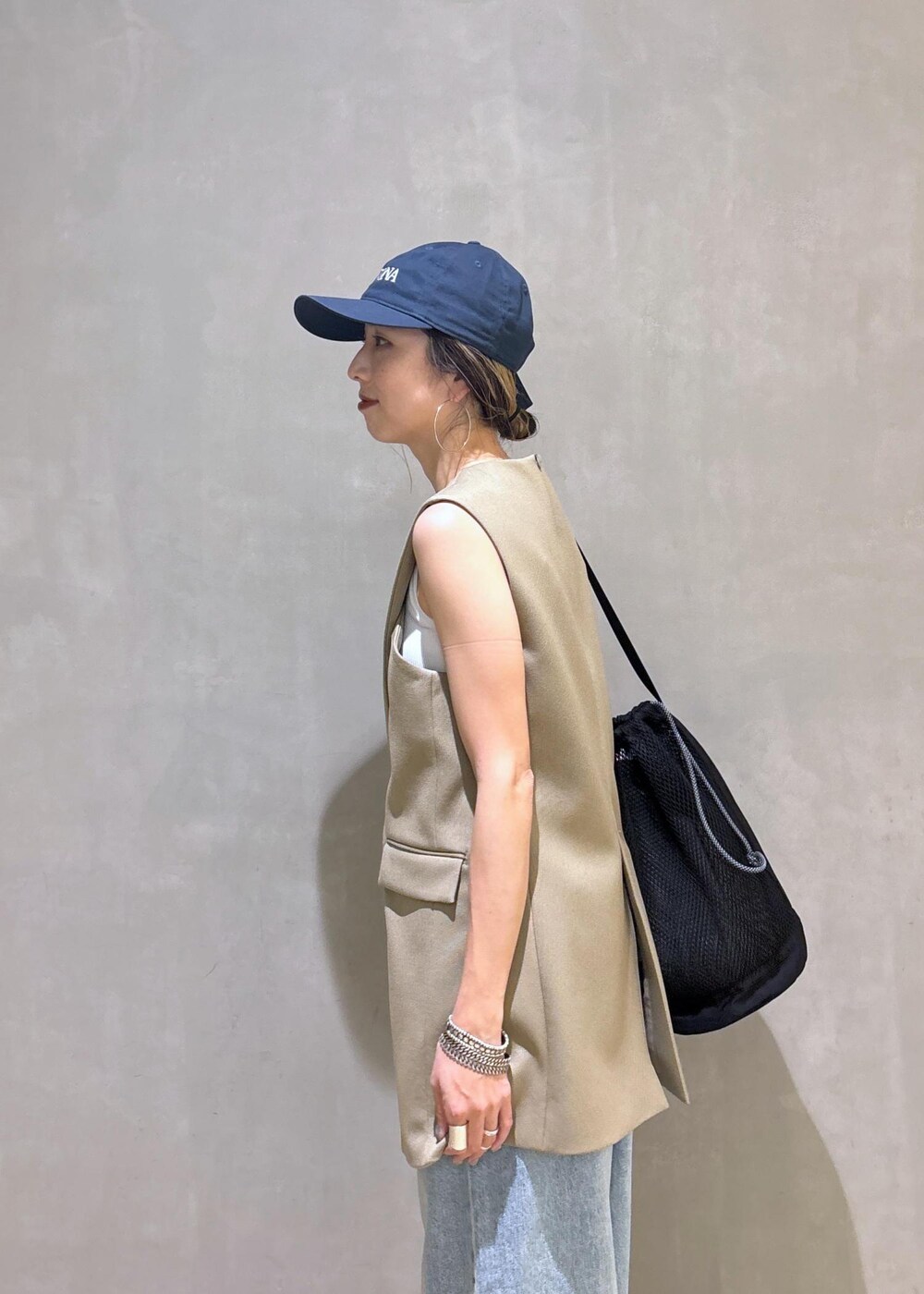 ベージュ系のベスト、ブラック系のスニーカー、ブラック系のショルダーバッグを着用したレディースの夏コーディネートの9枚目の写真