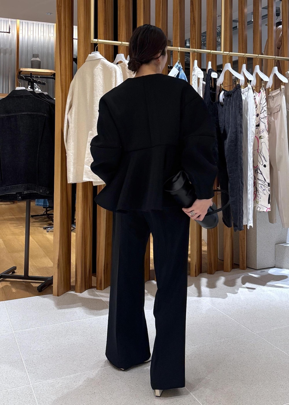ブラック系のショルダーバッグ、ホワイト系のパンプス、ブラック系のスラックスを着用したレディースの冬コーディネートの4枚目の写真