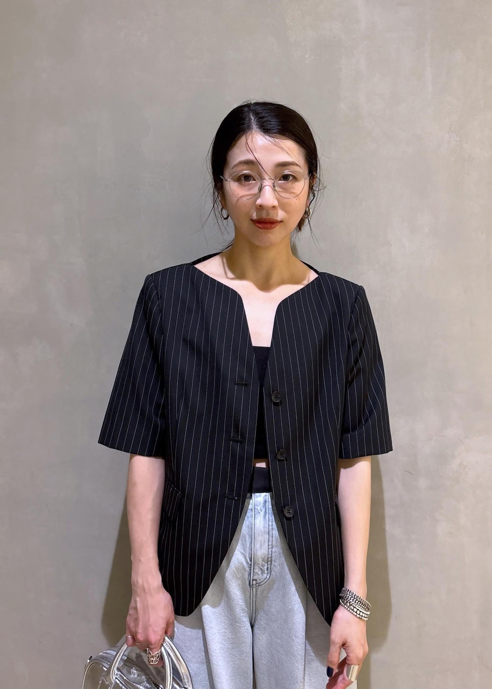 ブルー系のデニムパンツ、ブラック系のノーカラージャケット、シルバー系のボストンバッグを着用したレディースの春コーディネートの8枚目の写真