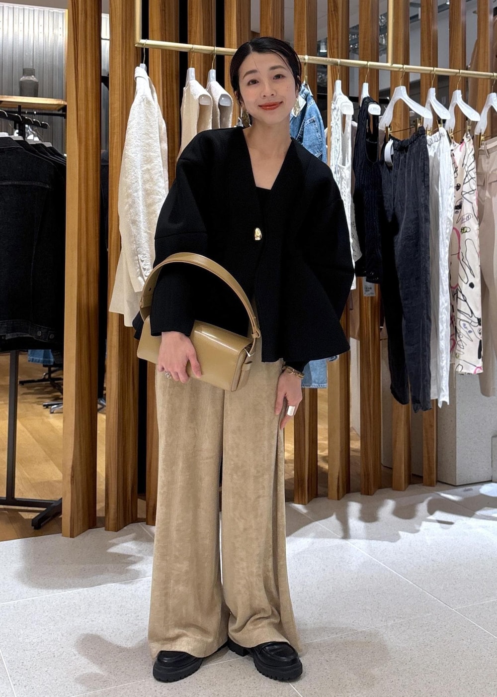 ベージュ系のハンドバッグ、ブラック系のローファー、ブラック系のカーディガン/ボレロを着用したレディースの冬コーディネートの2枚目の写真