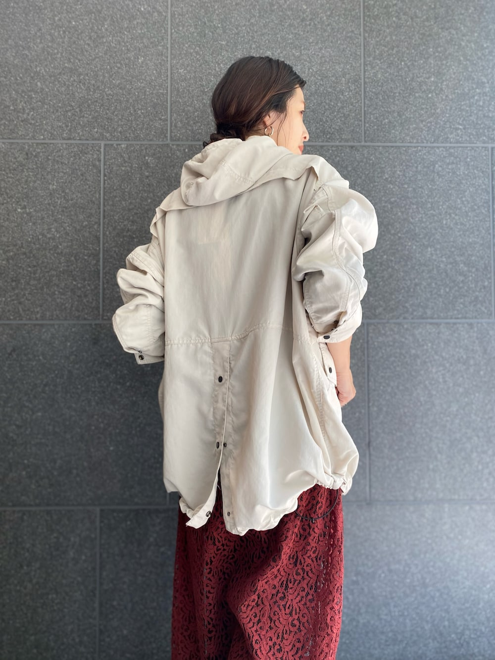 ホワイト系のマウンテンパーカー、レッド系のワンピース/ドレス、ブラック系のブーツを着用したレディースの春コーディネートの2枚目の写真