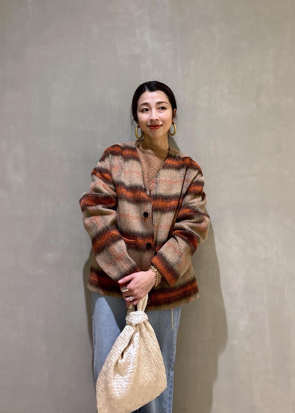 ホワイト系のハンドバッグ、ゴールド系のショルダーバッグ、ブルー系のデニムパンツを着用したレディースの冬コーディネートの8枚目の写真