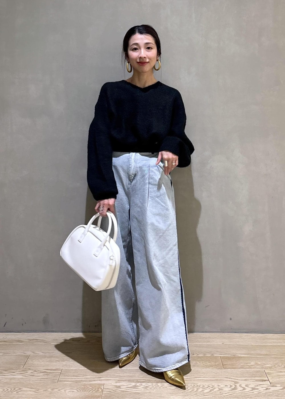 ブラック系のニット/セーター、ホワイト系のボストンバッグ、ブルー系のその他パンツを着用したレディースの冬コーディネートの2枚目の写真