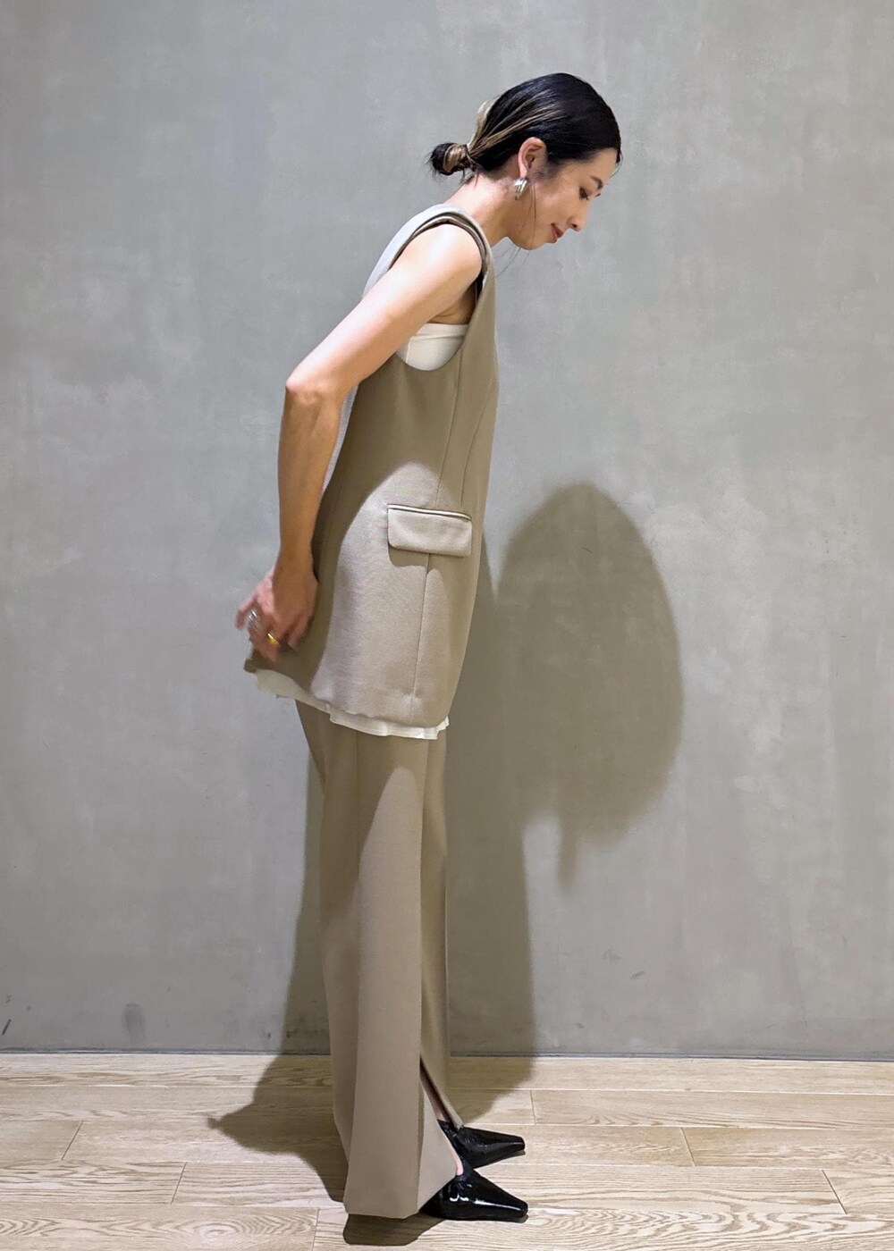 ブラック系のパンプス、ベージュ系のベスト、ベージュ系のスラックスを着用したレディースの夏コーディネートの3枚目の写真