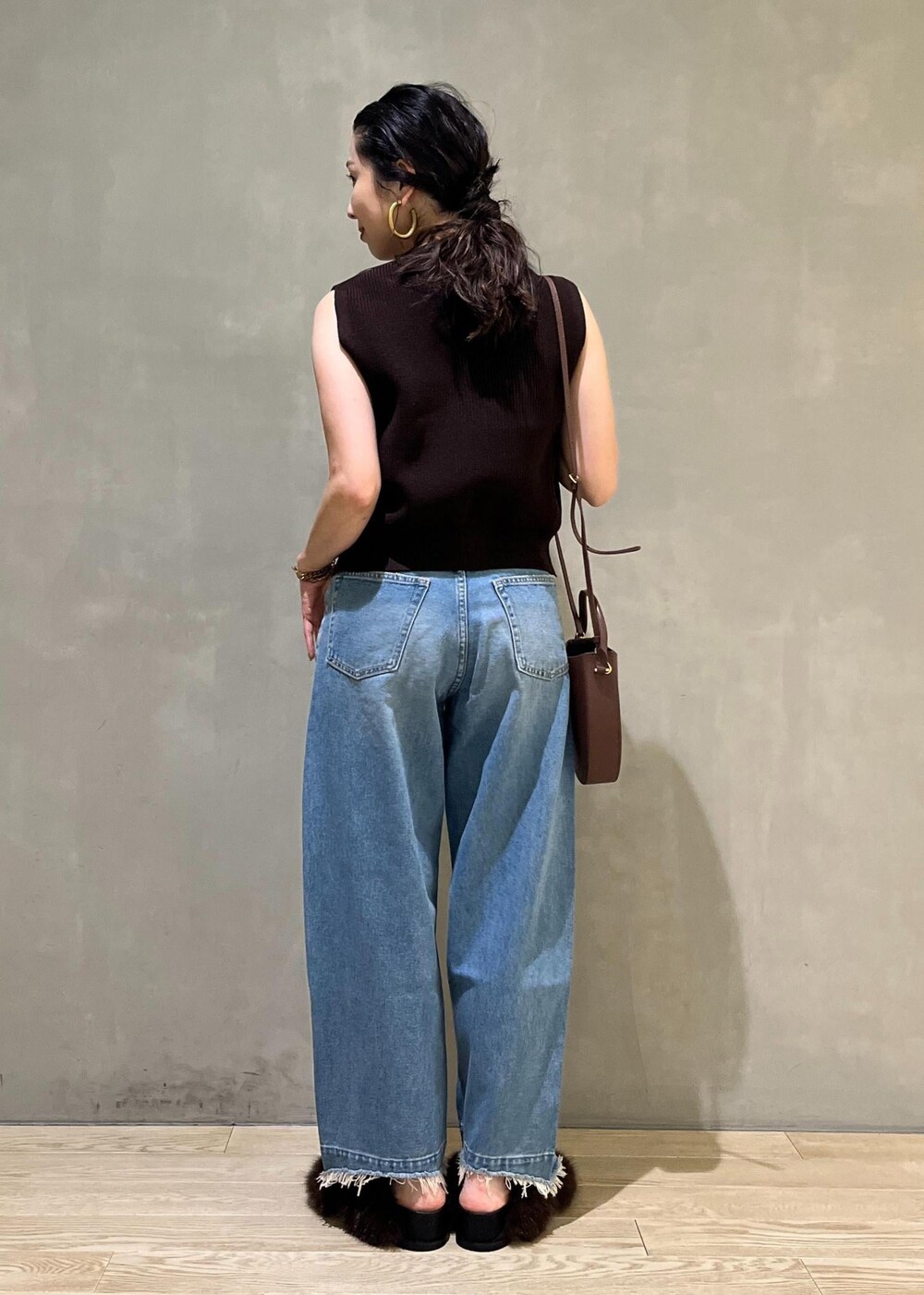 ブルー系のデニムパンツ、ブラウン系のサンダル、ブラウン系のベストを着用したレディースの夏コーディネートの3枚目の写真