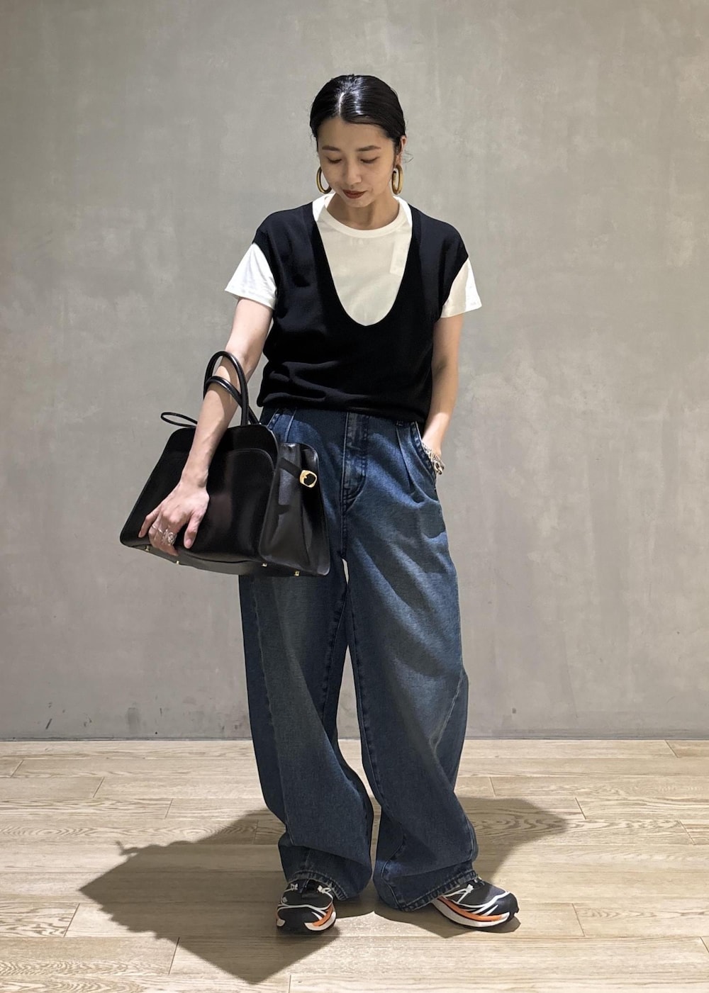 ブラック系のトートバッグ、ブラック系のTシャツ/カットソー、ブルー系のデニムパンツを着用したレディースの夏コーディネートの2枚目の写真