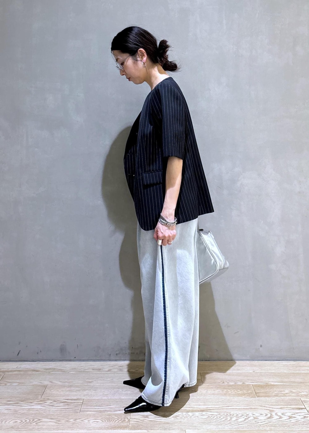 ブルー系のデニムパンツ、ブラック系のノーカラージャケット、シルバー系のボストンバッグを着用したレディースの春コーディネートの5枚目の写真